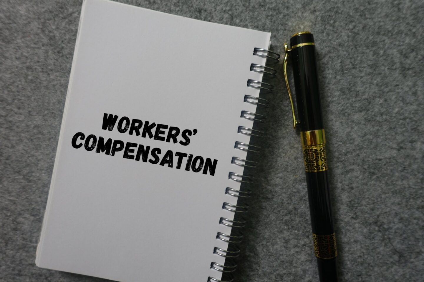 A notebook that says workers' compensation next to a pen