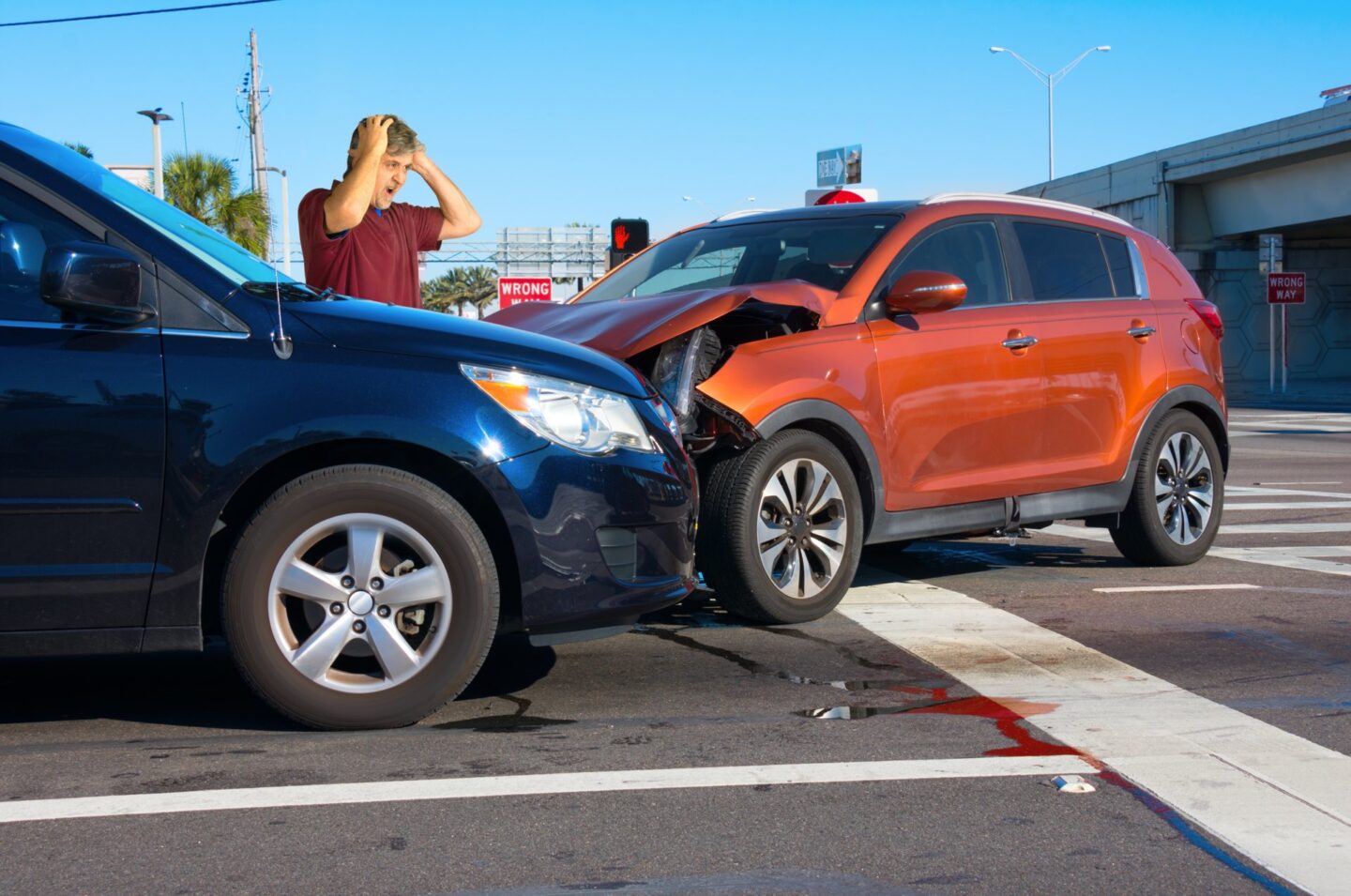 Two cars wrecked into each other and a man holding his hands on his head