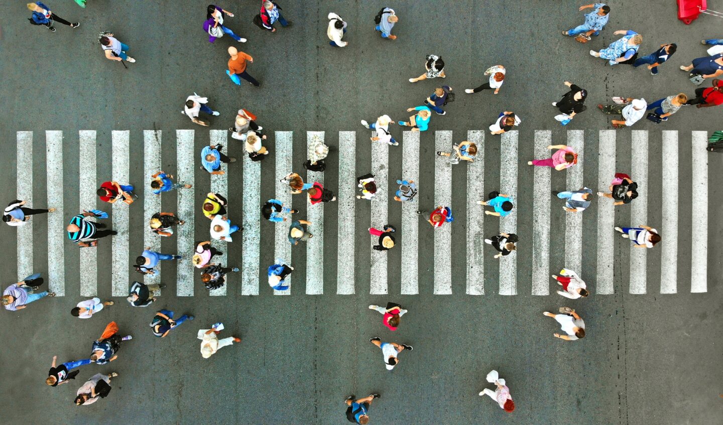 An aerial view of a large number of people walking across a crosswalk.
