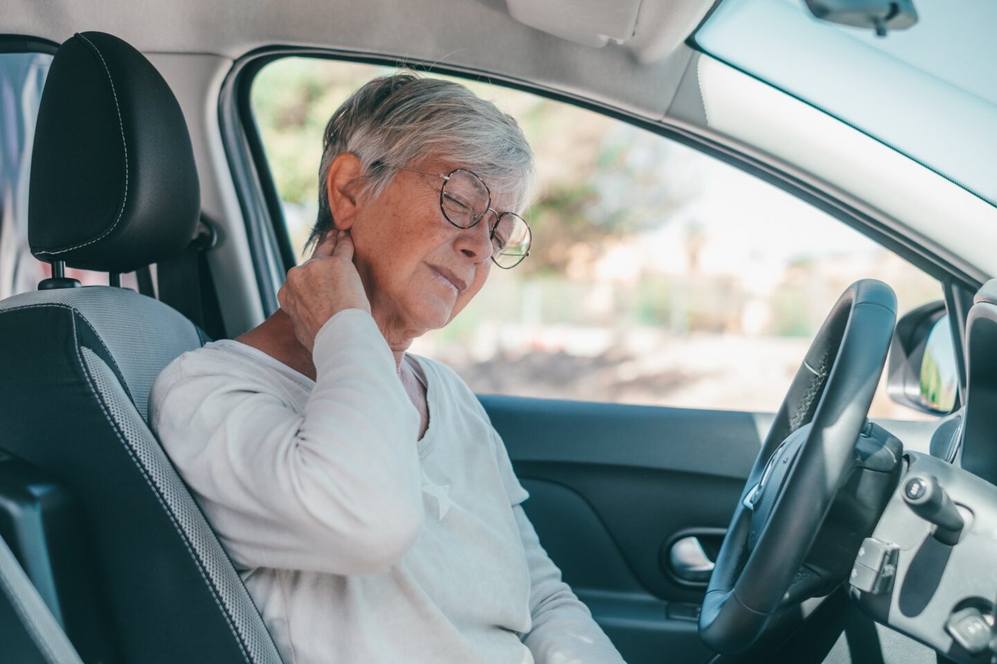 Woman holding her neck sitting in a car