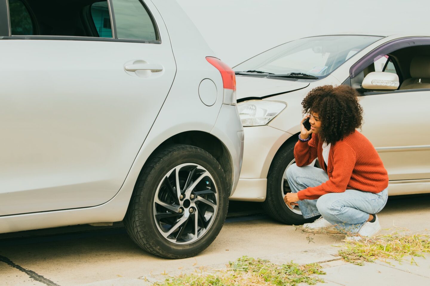 Woman on the phone looking at two wrecked vehicles