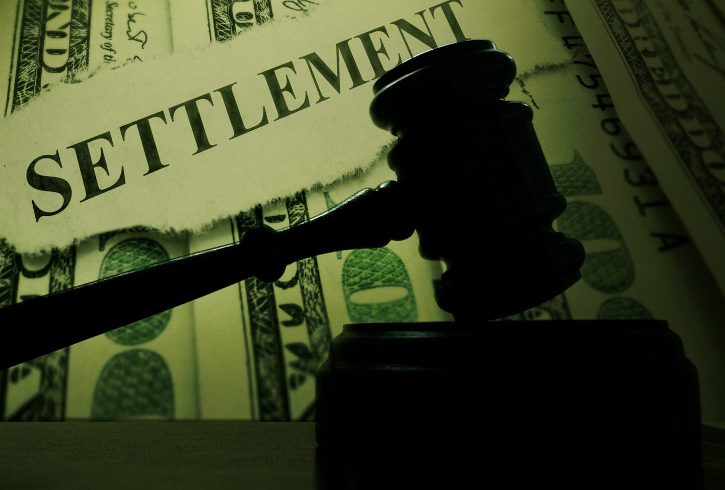 A silhouette of a gavel resting on its stand in front of money and the word settlement.